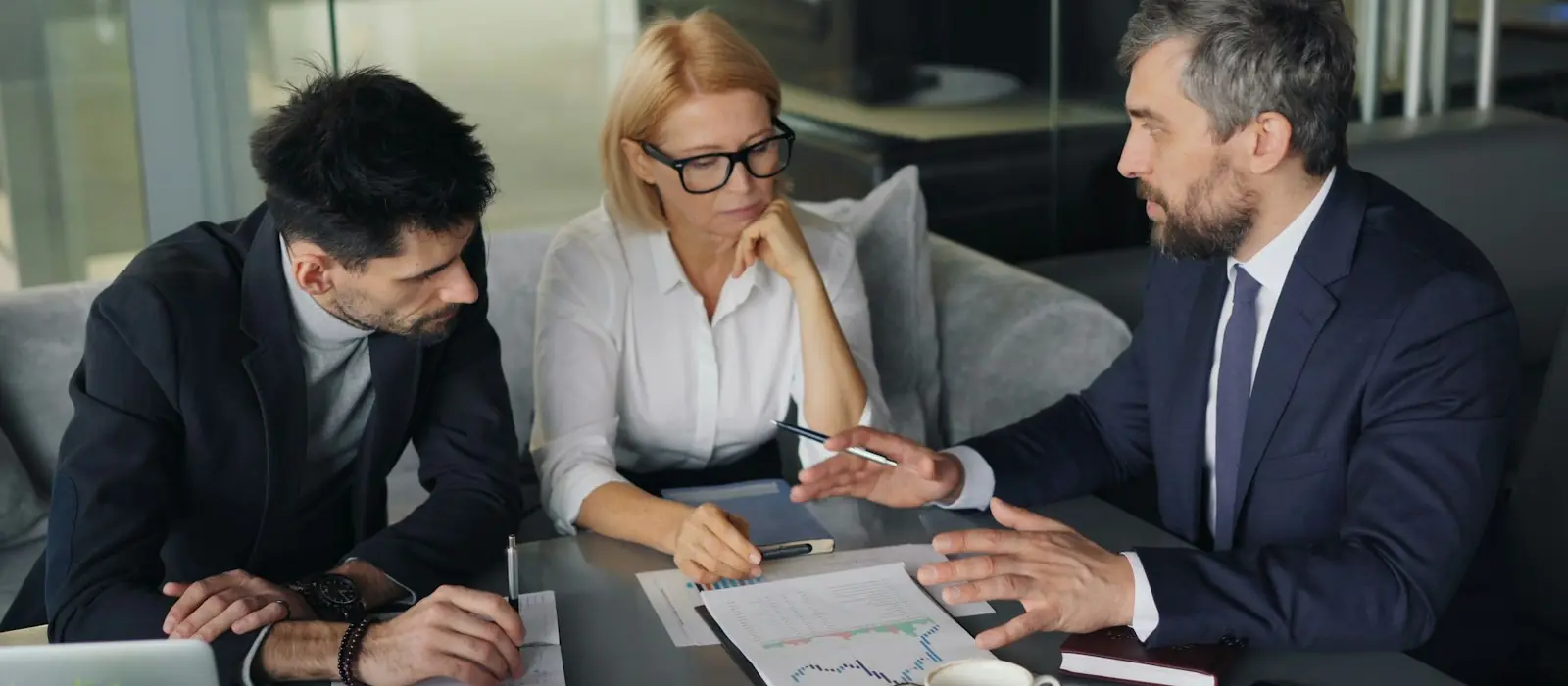 Three colleagues reviewing charts in a meeting