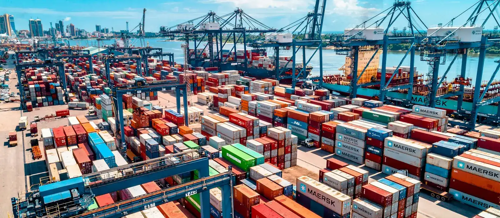 Stacked shipping containers and cranes at a port